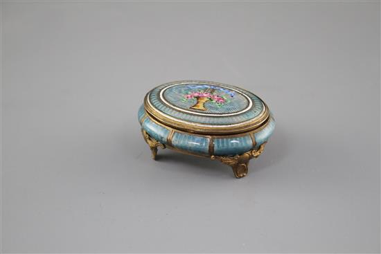 A late 19th century gilt metal and enamel oval box, decorated with a basket of flowers,